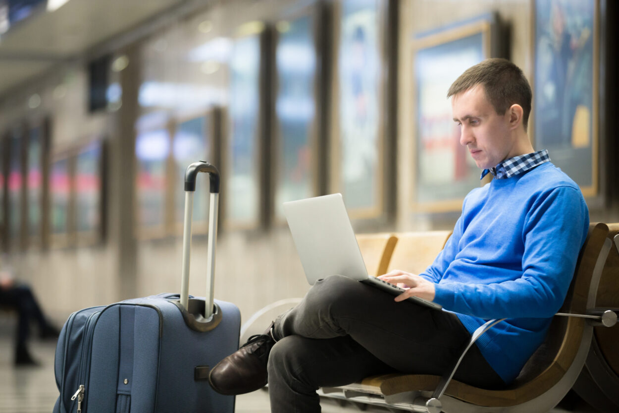 Freelancer traveler waiting at transport station Business visitor reviewing documents while waiting at a transport station — representing the process for Canada's Business Visitor Visa.