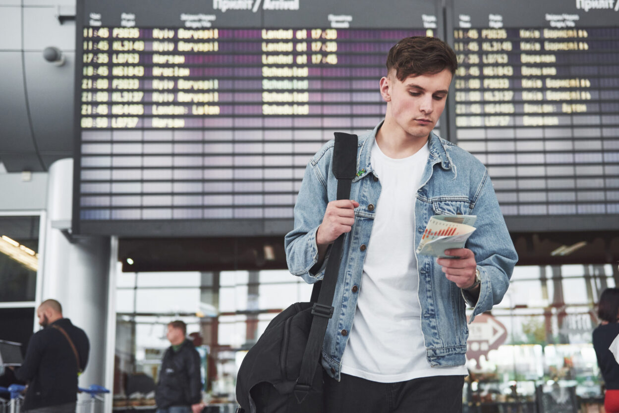 The man expects his flight at the airport. Male traveler waiting at the airport before departure, preparing documents for visitor visas to Canada